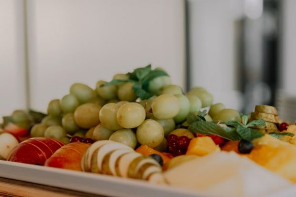 A vibrant assortment of fruits including grapes, apples, and berries on a white tray.